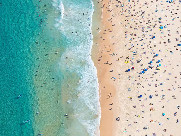 Aerial photograph of people resting on a beach, and playing in the water